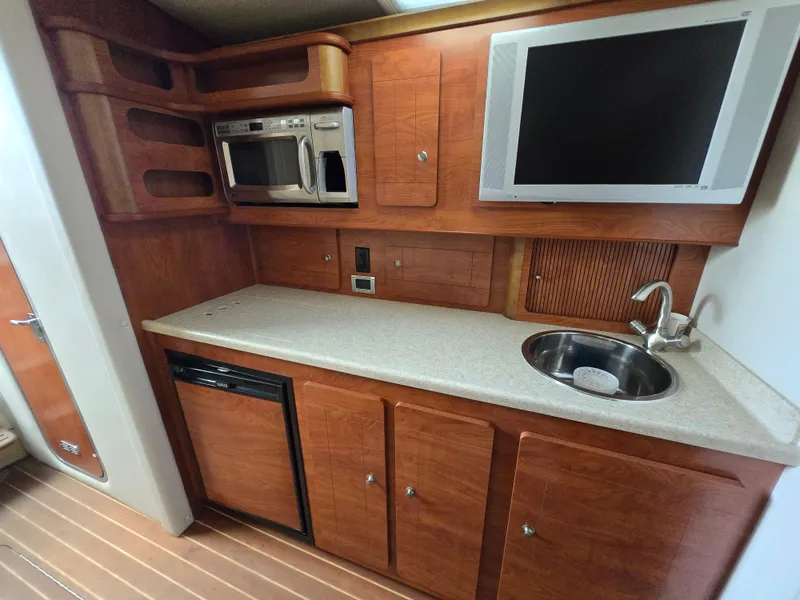 Slide: The Image of 2008 Rinker 400 Express Cruiser kitchen with microwave, sink, and TV. - 13