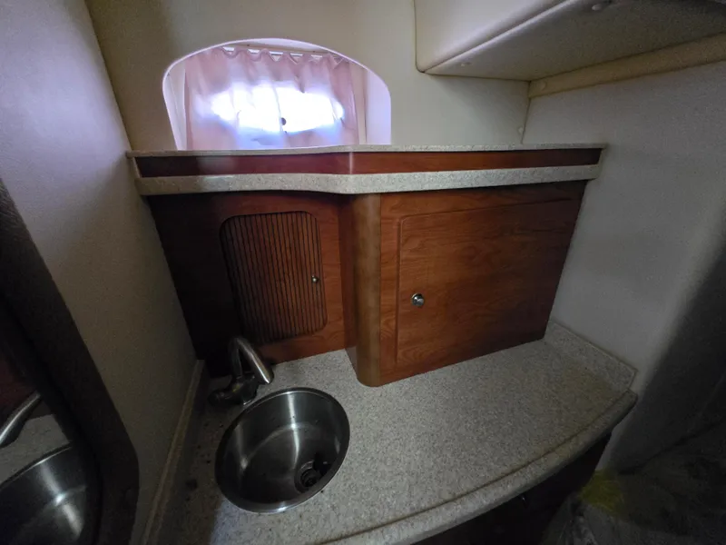 Slide: The Image of 2008 Rinker 400 Express Cruiser bathroom sink with wooden cabinetry and small window. - 14