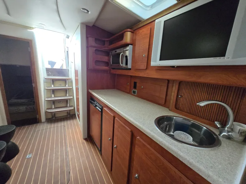 Slide: The Image of 2008 Rinker 400 Express Cruiser interior with kitchenette, sink, and TV. - 18