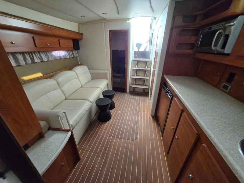 Slide: The Image of 2008 Rinker 400 Express Cruiser interior with sofa, kitchenette, and wooden flooring. - 2