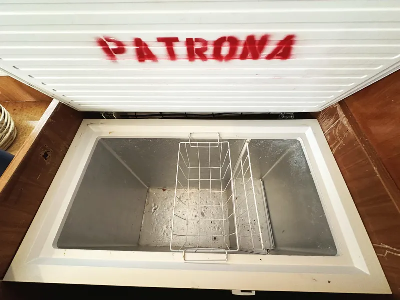 Slide: The Image of Open freezer on Mikelson 61 Sportfisher boat, labeled "PATRONA," with empty interior and wire basket. - 29