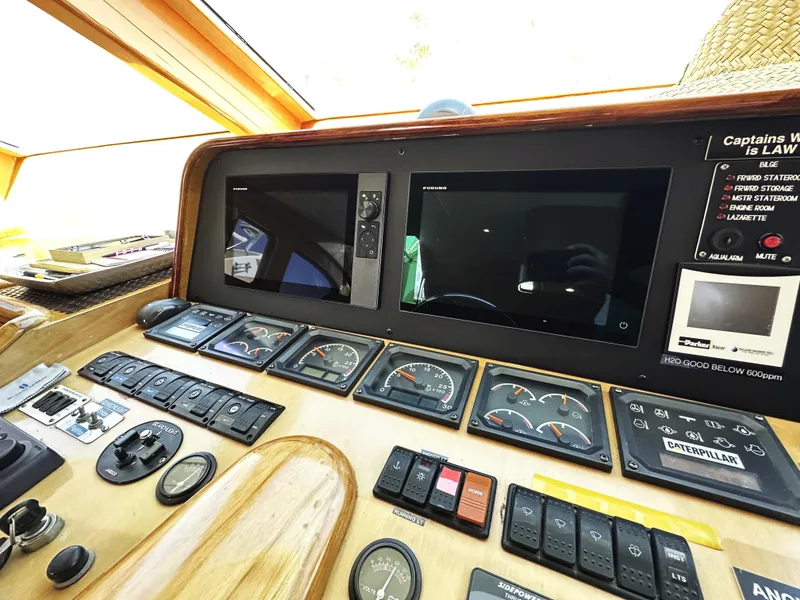 Slide: The Image of Control panel of a 2000 Mikelson 61 Sportfisher boat with gauges and screens. - 32
