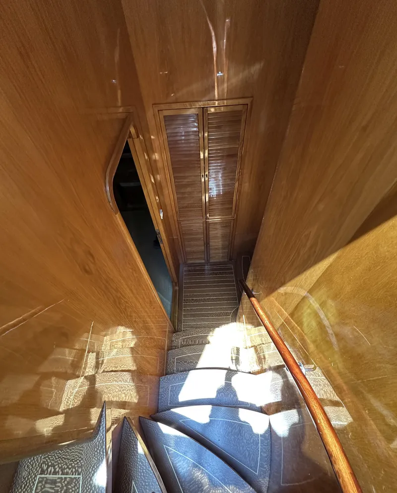 Slide: The Image of Staircase inside 2000 Mikelson 61 Sportfisher yacht with wooden paneling and carpeted steps. - 34