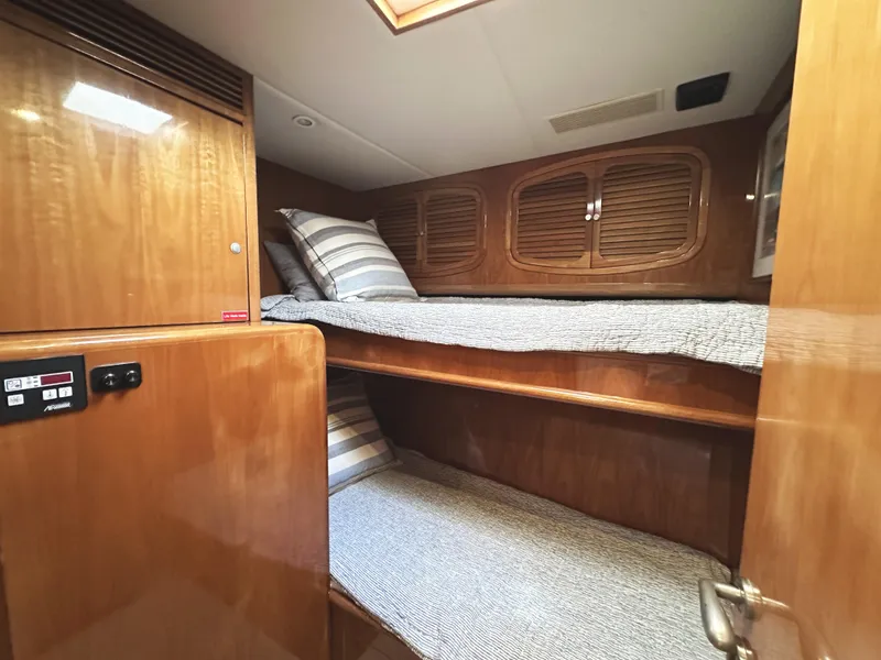 Slide: The Image of Interior of 2000 Mikelson 61 Sportfisher with wooden bunk beds and striped bedding. - 46