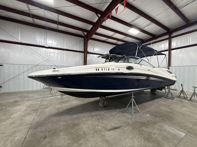 The Image of 2013 Sea Ray 300 Sundeck boat in storage, blue and white exterior, indoor facility. - 0