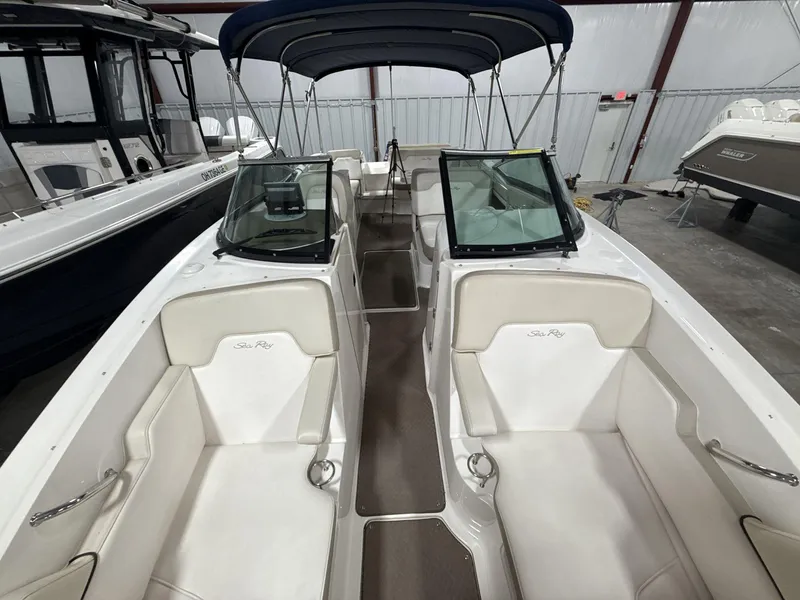 Slide: The Image of 2013 Sea Ray 300 Sundeck boat interior with white seating and canopy in storage. - 16