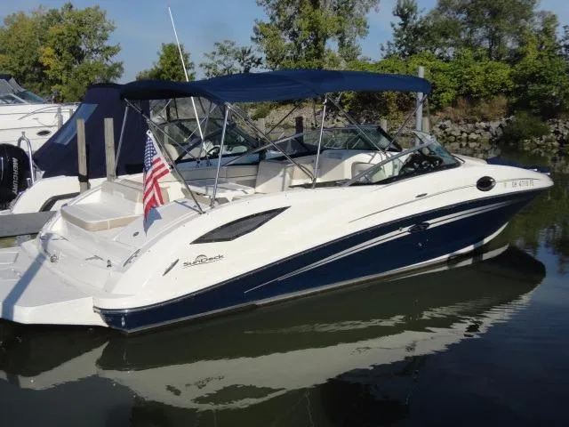 Slide: The Image of 2013 Sea Ray 300 Sundeck boat docked with canopy and American flag. - 18