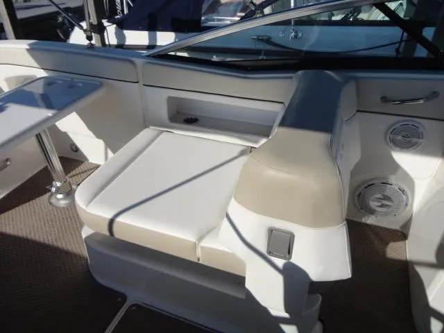 Slide: The Image of 2013 Sea Ray 300 Sundeck interior with beige seating and table. - 24