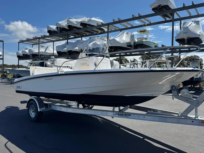 Slide: The Image of 2007 Boston Whaler 200 Dauntless boat on trailer, parked in marina with stacked boats. - 3