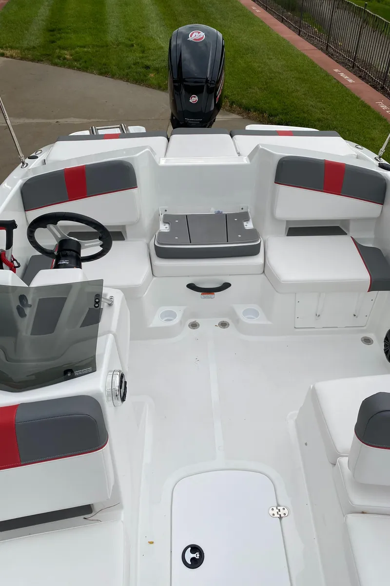 Slide: The Image of 2025 Tahoe T18 boat interior with seating, steering wheel, and motor, on a grassy background. - 4