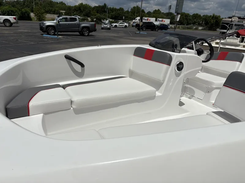 Slide: The Image of 2025 Tahoe T16 boat interior with white and red seating in a parking lot. - 2