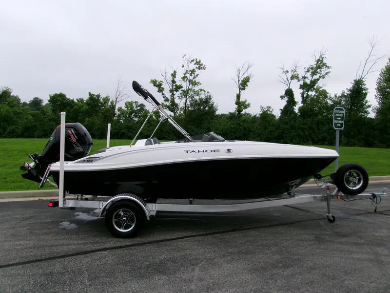 The Image of 2025 Tahoe T18 boat on trailer, parked on road with green trees in background. - 0