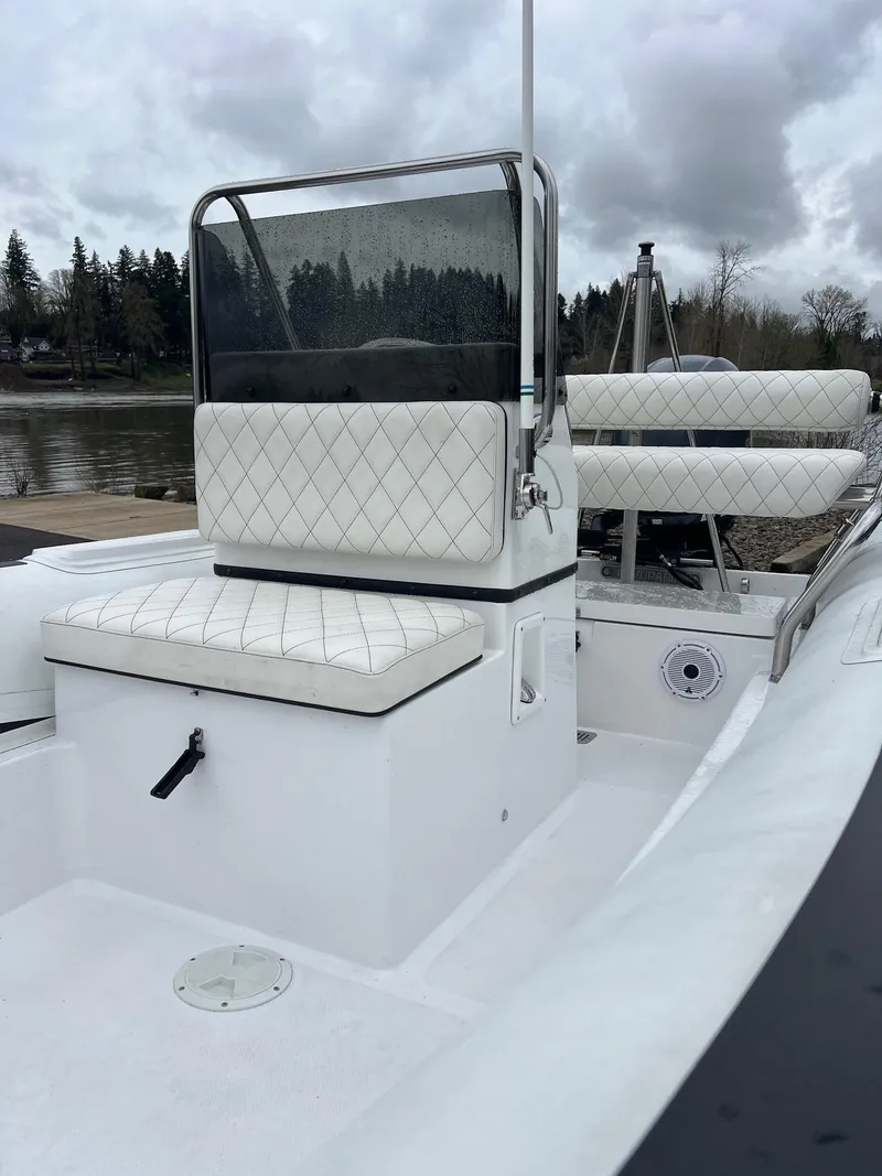 Slide: The Image of 2024 Novurania DL 550 boat with white seating, docked by a lake under cloudy skies. - 14