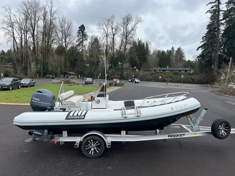 Slide: The Image of 2024 Novurania DL 550 boat on trailer in parking lot, surrounded by trees. - 3