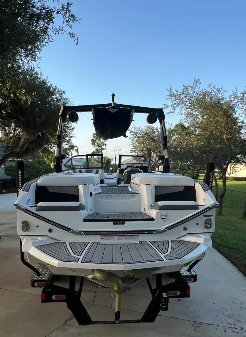 Slide: The Image of 2022 Nautique Super Air G23 boat on trailer, parked outdoors, surrounded by trees. - 4