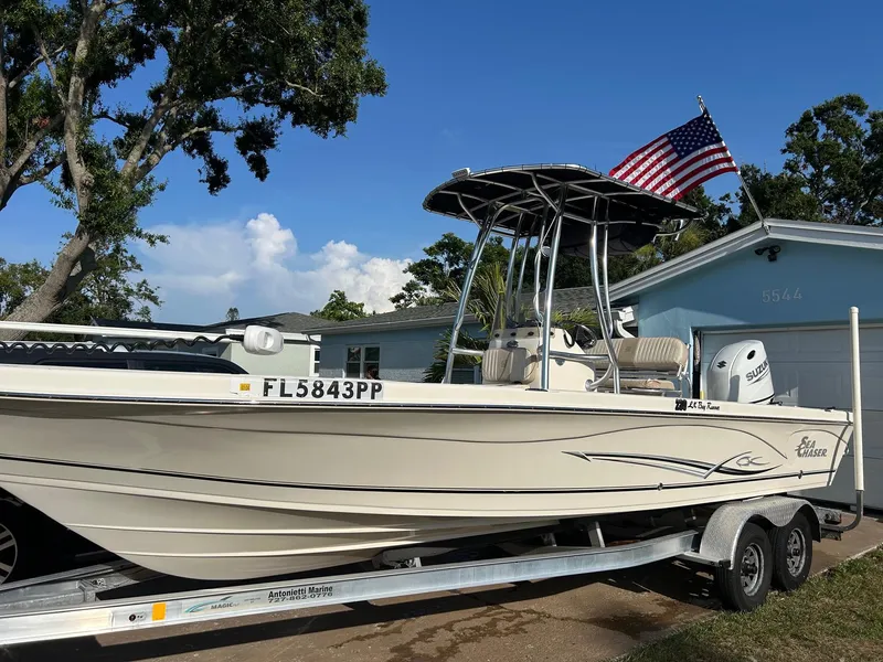 The Image of 2023 Sea Chaser 23 LX Bay Runner boat on trailer, American flag, residential background. - 0