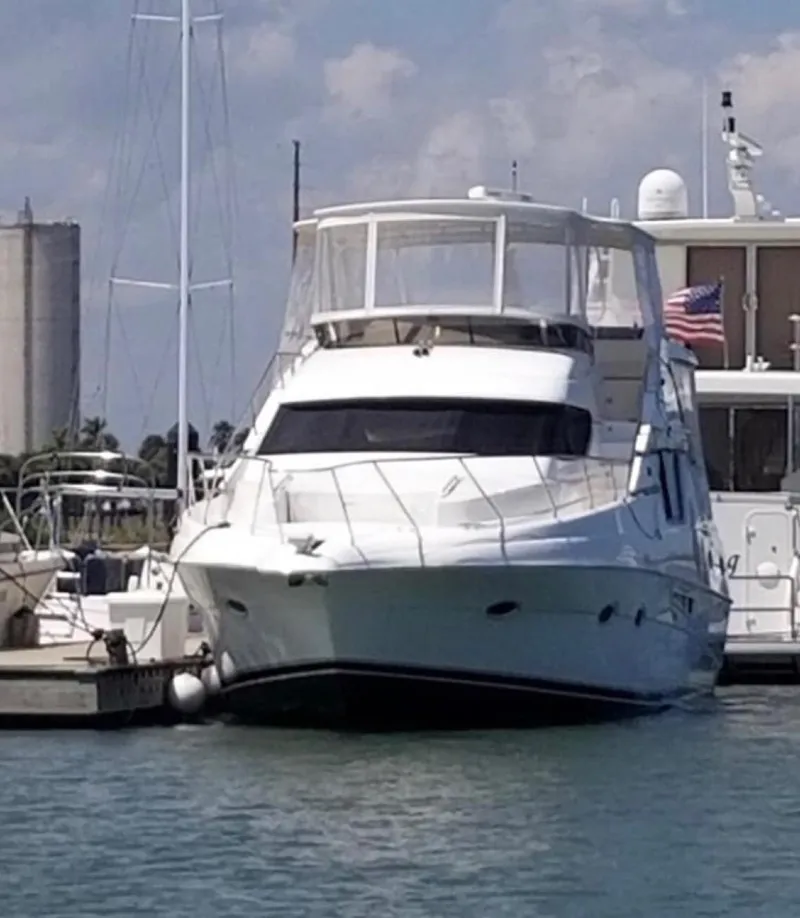 Slide: The Image of 1999 Silverton 453 Motor Yacht docked at marina with American flag. - 2