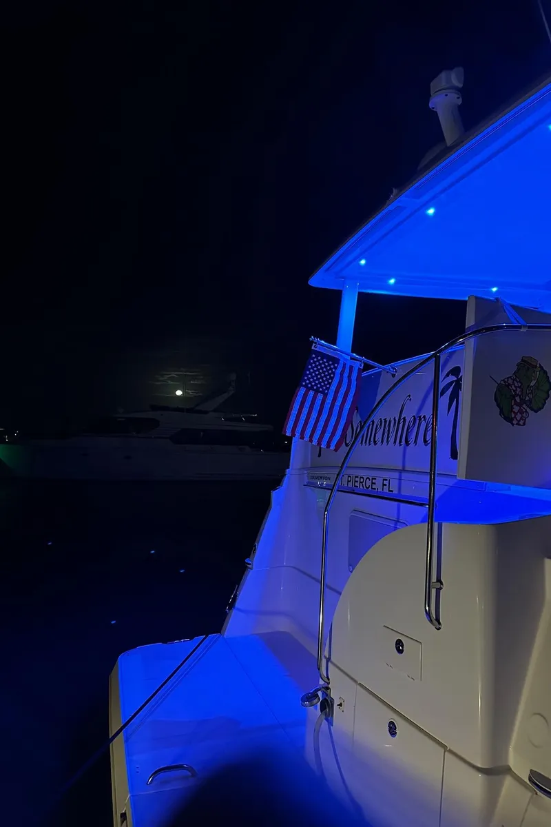 Slide: The Image of 1999 Silverton 453 Motor Yacht illuminated at night with blue lights and an American flag. - 29