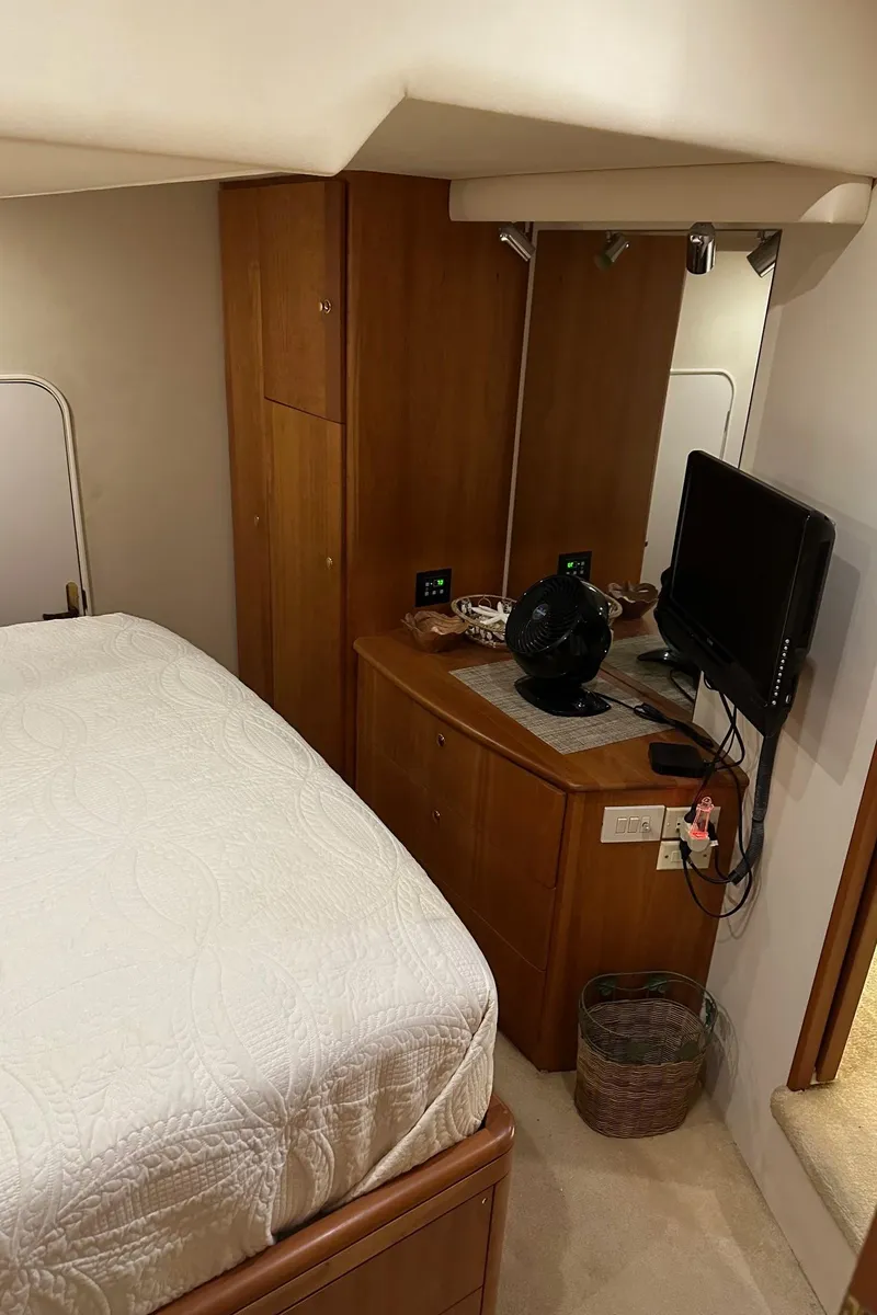Slide: The Image of 1999 Silverton 453 Motor Yacht bedroom with TV, fan, and wooden cabinetry. - 35