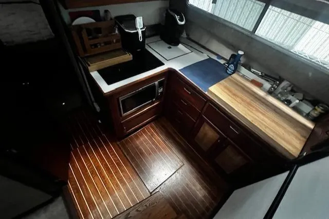 Slide: The Image of 1985 Bayliner 3870 Motoryacht kitchen with wood flooring, countertop, and appliances. - 14