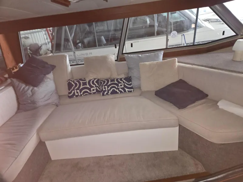 Slide: The Image of Interior of 1985 Bayliner 3870 Motoryacht with Flybridge, featuring cozy seating and cushions. - 3