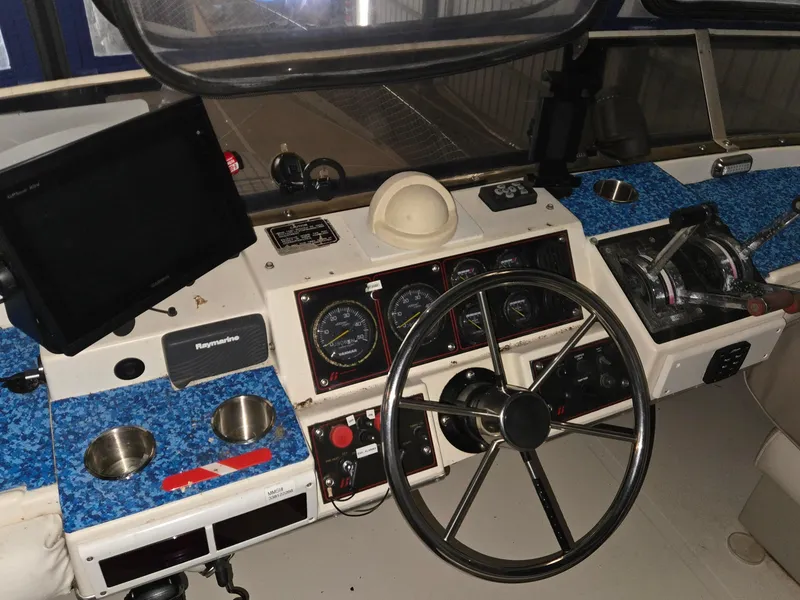 Slide: The Image of 1985 Bayliner 3870 Motoryacht helm with flybridge, featuring steering wheel and navigation instruments. - 32