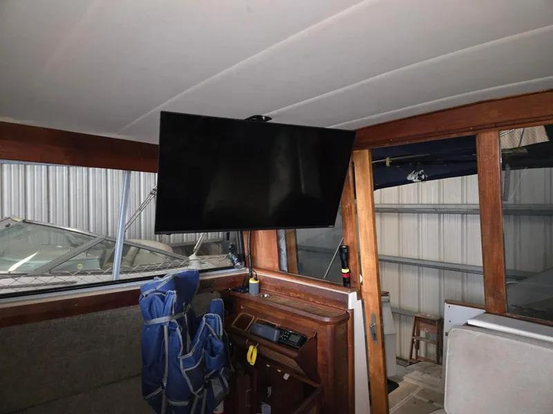 Slide: The Image of Interior of 1985 Bayliner 3870 Motoryacht with flybridge, featuring a mounted TV and wooden cabinetry. - 4