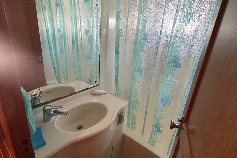 Slide: The Image of Compact bathroom with a white sink and starfish-patterned shower curtain in a 1999 Selene 43. - 34