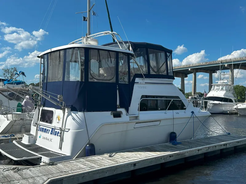 Slide: The Image of 1997 Mainship 34' M/Y docked, featuring blue canopy and clear skies. - 1