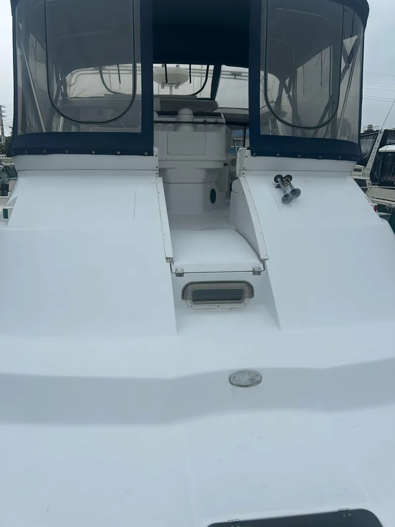 Slide: The Image of 1997 Mainship 34' M/Y yacht with enclosed cockpit and sleek white design. - 10