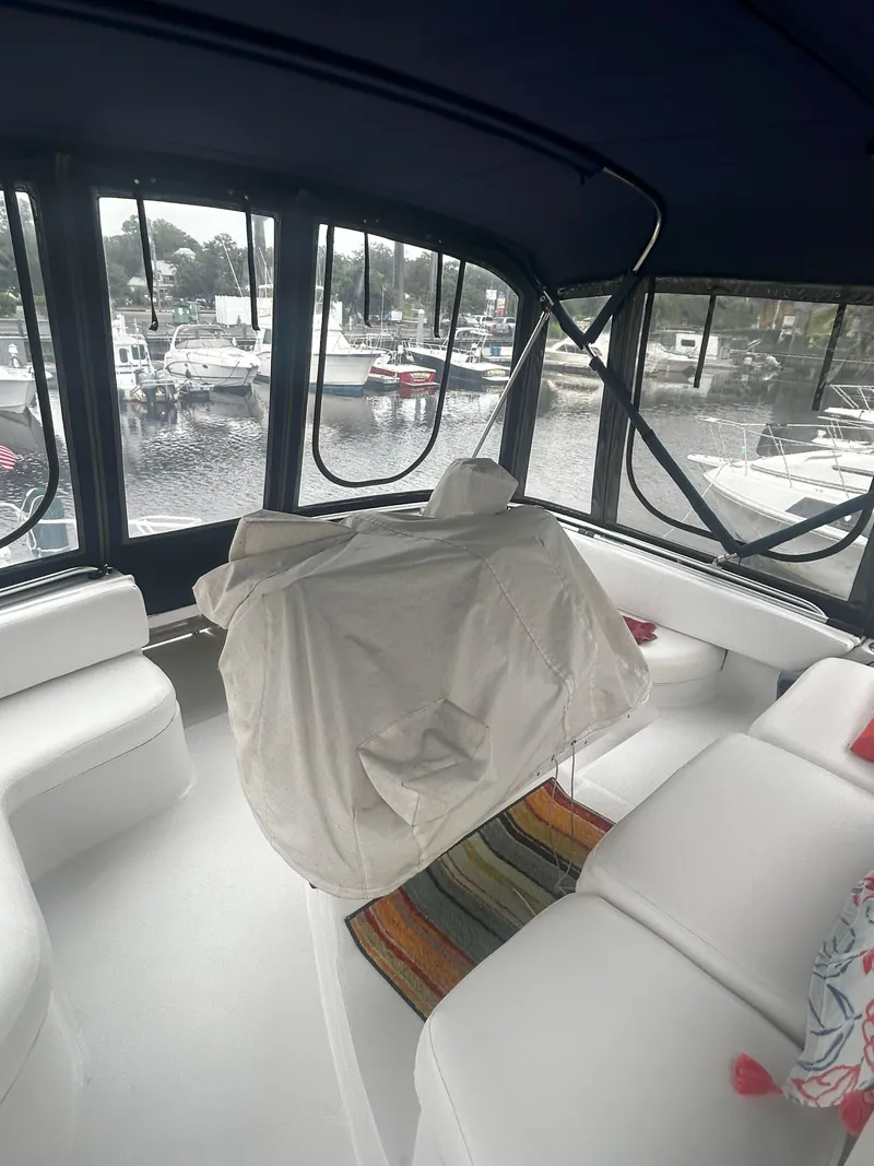 Slide: The Image of Interior of 1997 Mainship 34' M/Y yacht with white seating and marina view. - 7