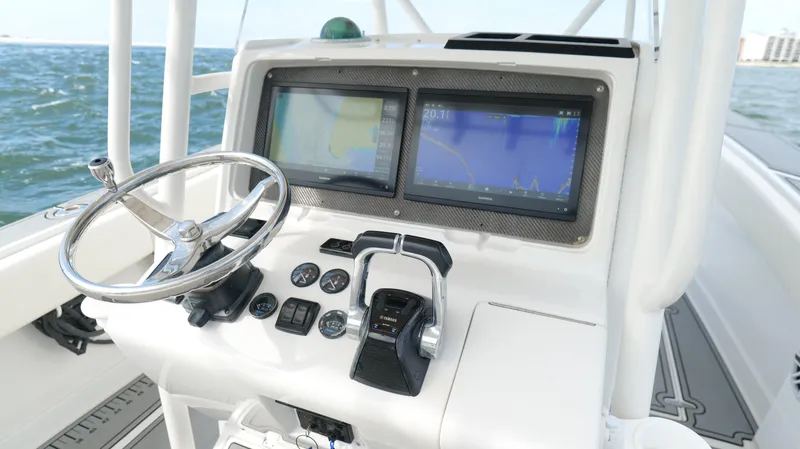 Slide: The Image of 2004 Jupiter 31 FS boat dashboard with steering wheel and navigation screens on open water. - 14