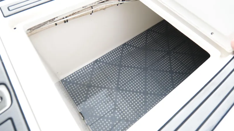 Slide: The Image of Open storage compartment on a 2004 Jupiter 31 FS boat, featuring a non-slip mat. - 44