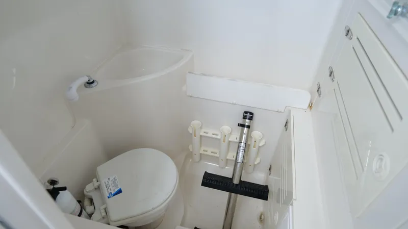 Slide: The Image of Compact bathroom in a 2004 Jupiter 31 FS boat, featuring a toilet and showerhead. - 45