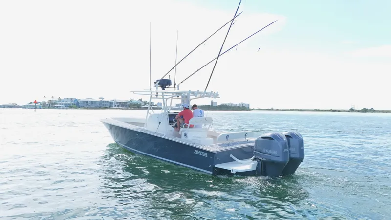 Slide: The Image of 2004 Jupiter 31 FS boat on calm water with fishing rods and dual engines. - 6