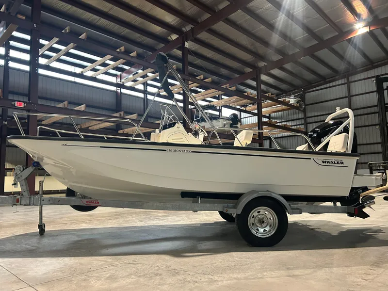 Slide: The Image of 2026 Boston Whaler 170 Montauk boat on trailer in warehouse setting. - 4
