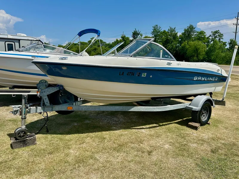 The Image of 2011 Bayliner 184 SF boat on trailer, parked on grass under clear blue sky. - 0