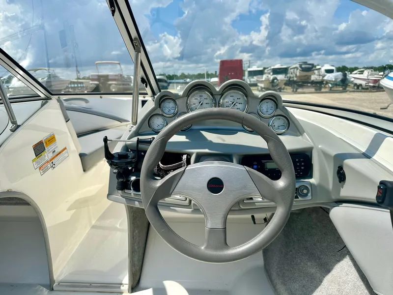 Slide: The Image of 2011 Bayliner 184 SF boat dashboard with steering wheel and gauges under a cloudy sky. - 14