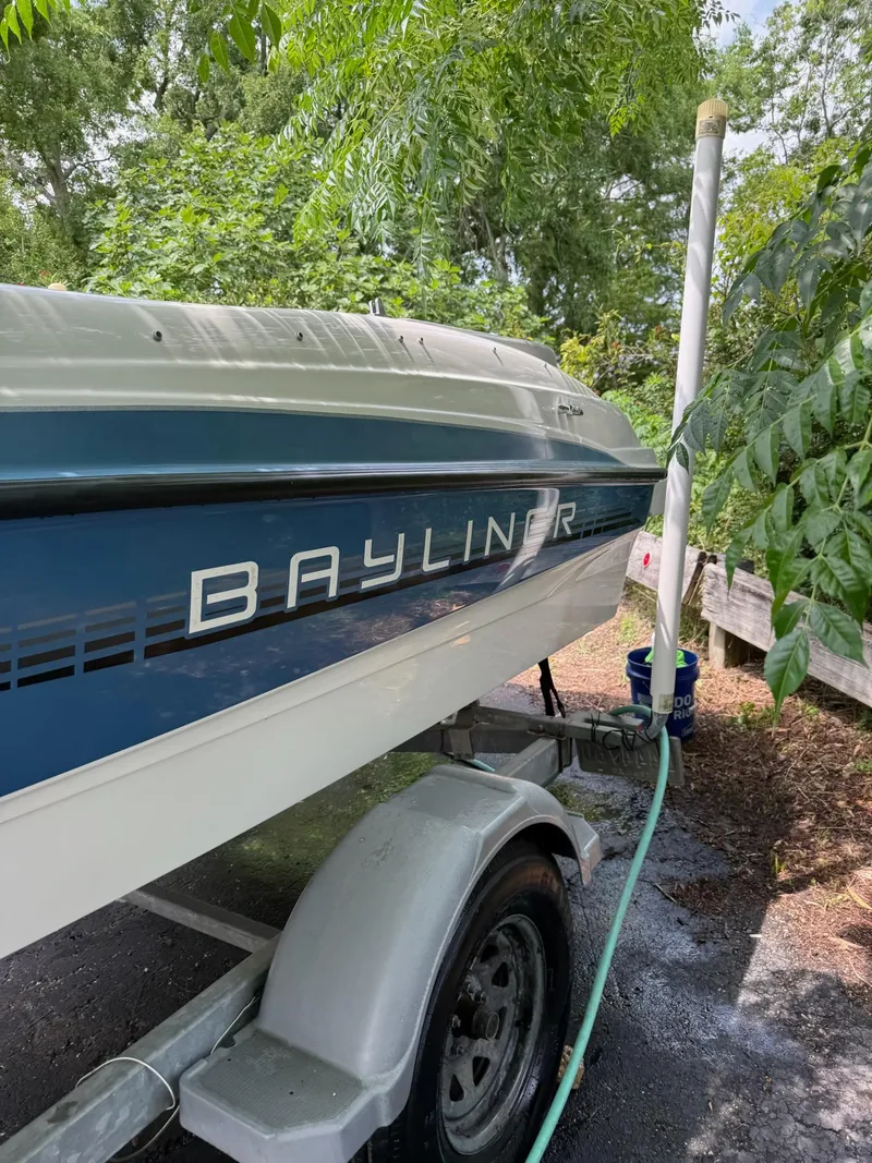 Slide: The Image of 2011 Bayliner 184 SF boat on trailer, surrounded by greenery. - 2