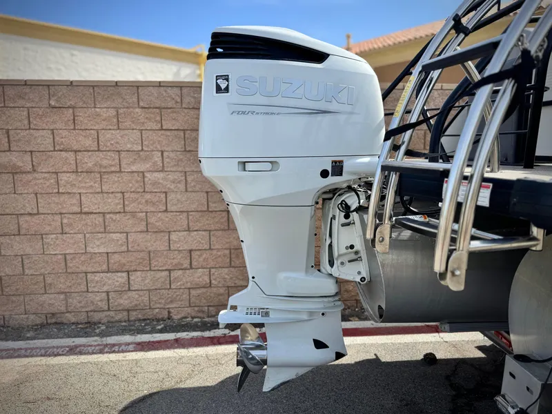 Slide: The Image of Outboard motor on a 2023 Godfrey Monaco 255 C boat, parked near a brick wall. - 7
