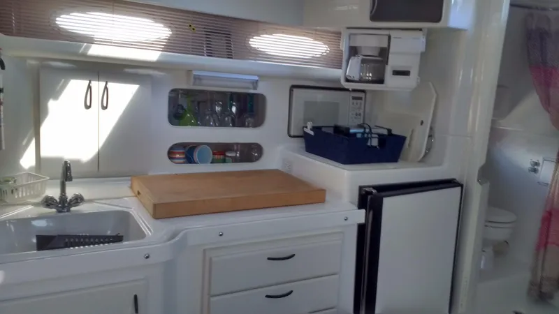 Slide: The Image of Interior of a 1996 Doral 350SC boat kitchen with sink, cutting board, and appliances. - 12