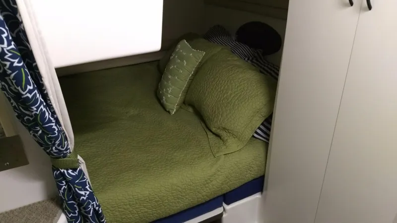 Slide: The Image of Cozy cabin bed in 1996 Doral 350SC boat with green bedding and patterned curtains. - 15
