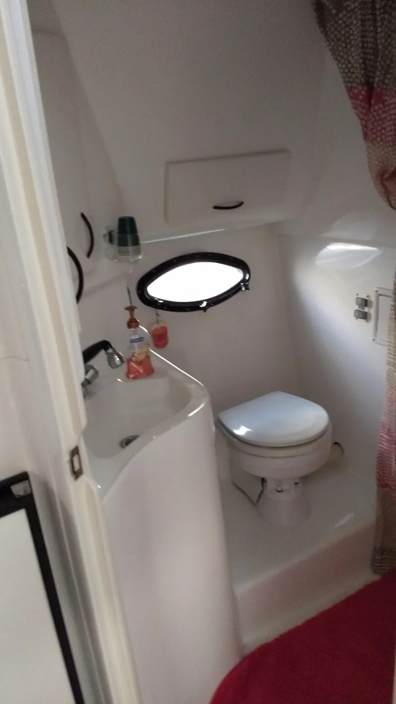 Slide: The Image of 1996 Doral 350SC boat bathroom with sink, toilet, and porthole window. - 19