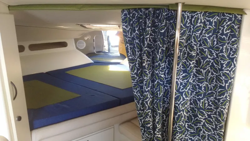 Slide: The Image of 1996 Doral 350SC cabin interior with blue and green bedding, patterned curtains. - 9