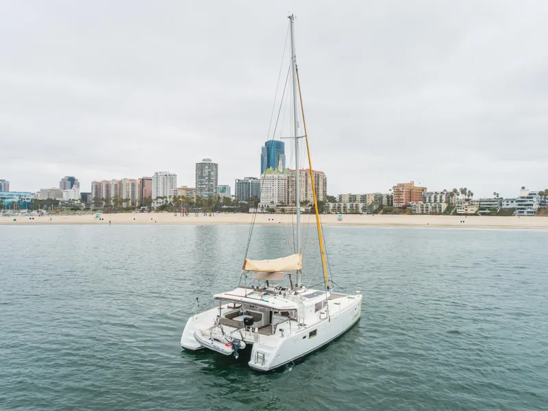 Slide: The Image of 2016 Lagoon 450F catamaran sailing near urban coastline with city skyline in background. - 10