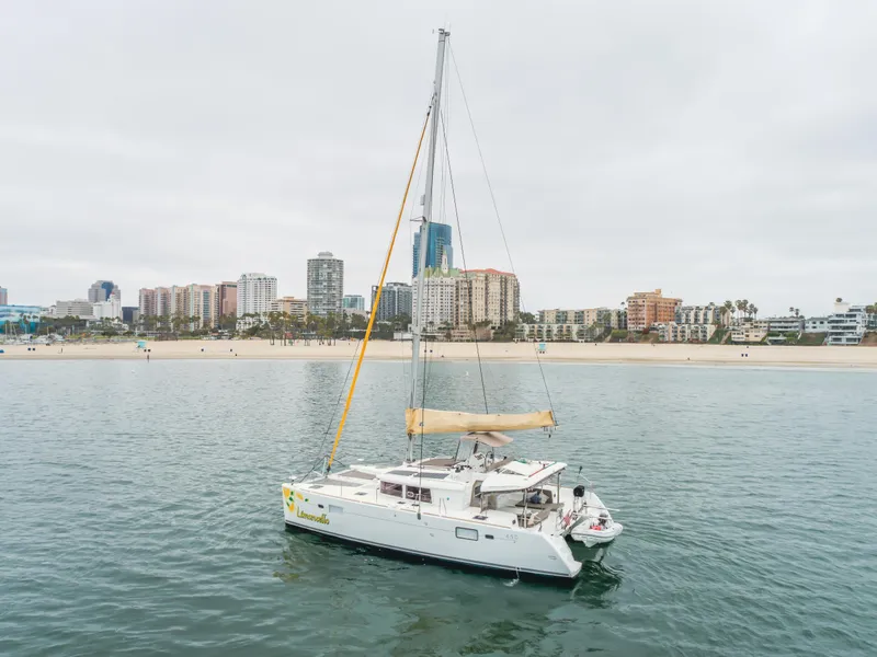 Slide: The Image of 2016 Lagoon 450F catamaran sailing near a city shoreline with buildings in the background. - 12