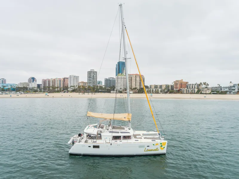 Slide: The Image of 2016 Lagoon 450F catamaran sailing near a city shoreline with buildings in the background. - 18