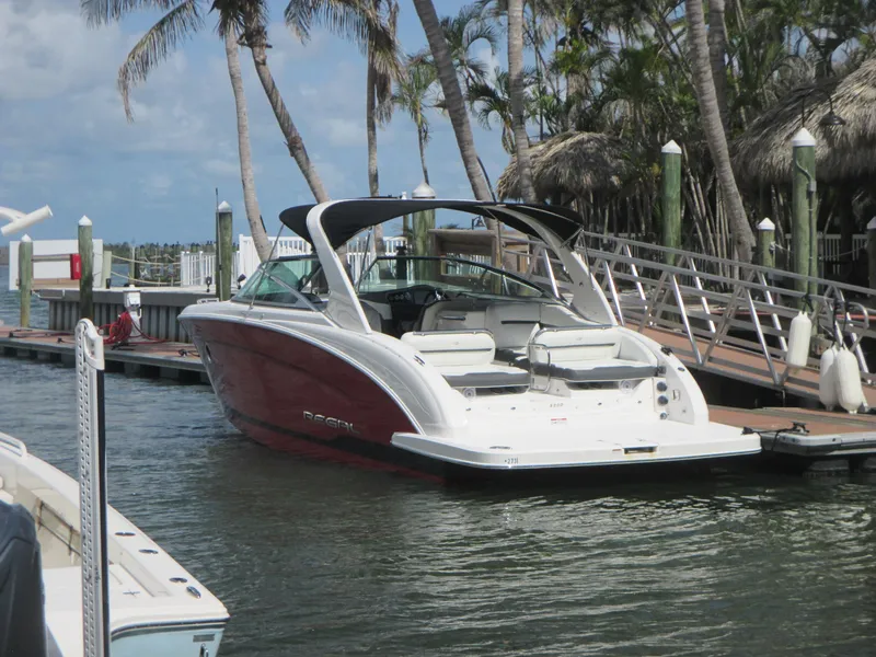 Slide: The Image of 2017 Regal 3200 Bowrider docked near palm trees, showcasing sleek design and spacious seating. - 2