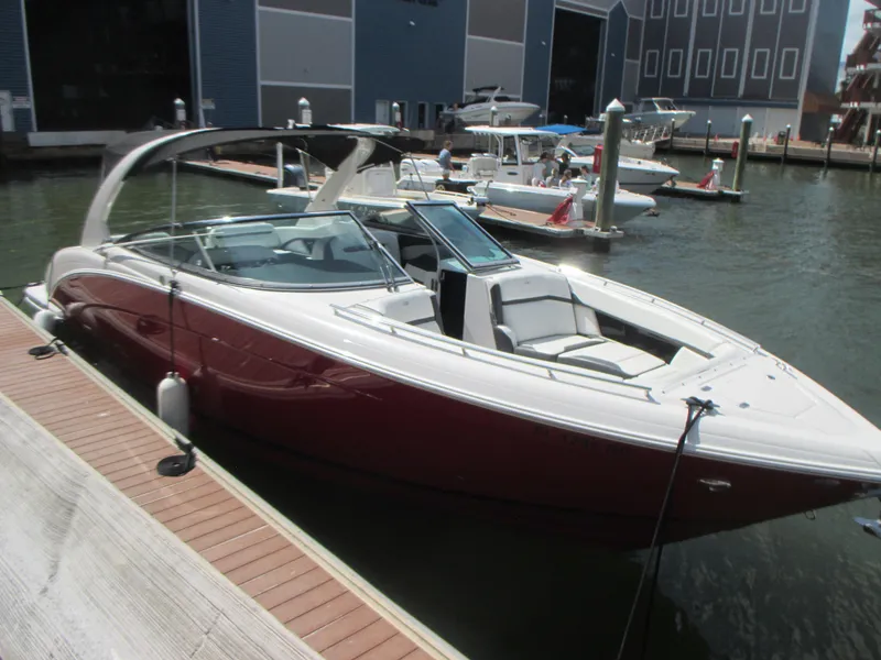 Slide: The Image of 2017 Regal 3200 Bowrider docked at marina, sleek design, red and white exterior. - 5