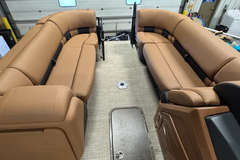 Slide: The Image of 2025 Regency 230 LE3 Sport boat interior with tan seating and carpeted floor. - 18